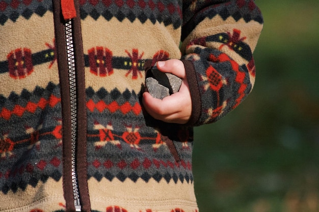 Foto mittelabschnitt eines kindes, das warme kleidung trägt, während es steine hält