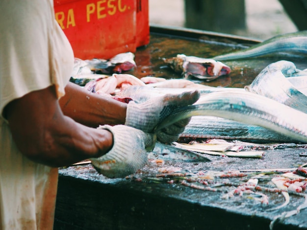 Foto mittelabschnitt eines mannes, der auf dem markt fisch hält