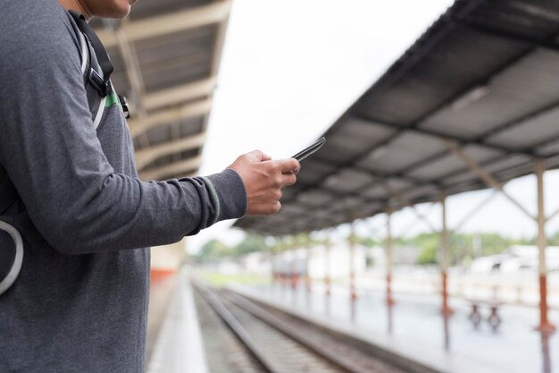 Foto mittelabschnitt eines mannes, der auf einem bahnhof ein handy benutzt