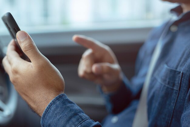 Foto mittelabschnitt eines mannes, der ein handy im auto benutzt