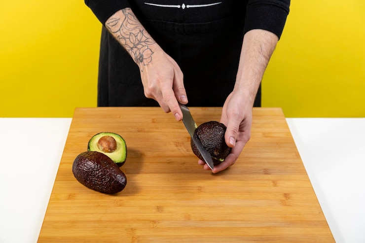 Foto mittelabschnitt eines mannes, der eine avocado auf dem tisch hält