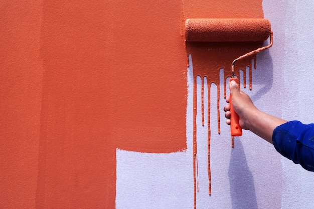 Mittelabschnitt eines Mannes, der eine orangefarbene Wand hält