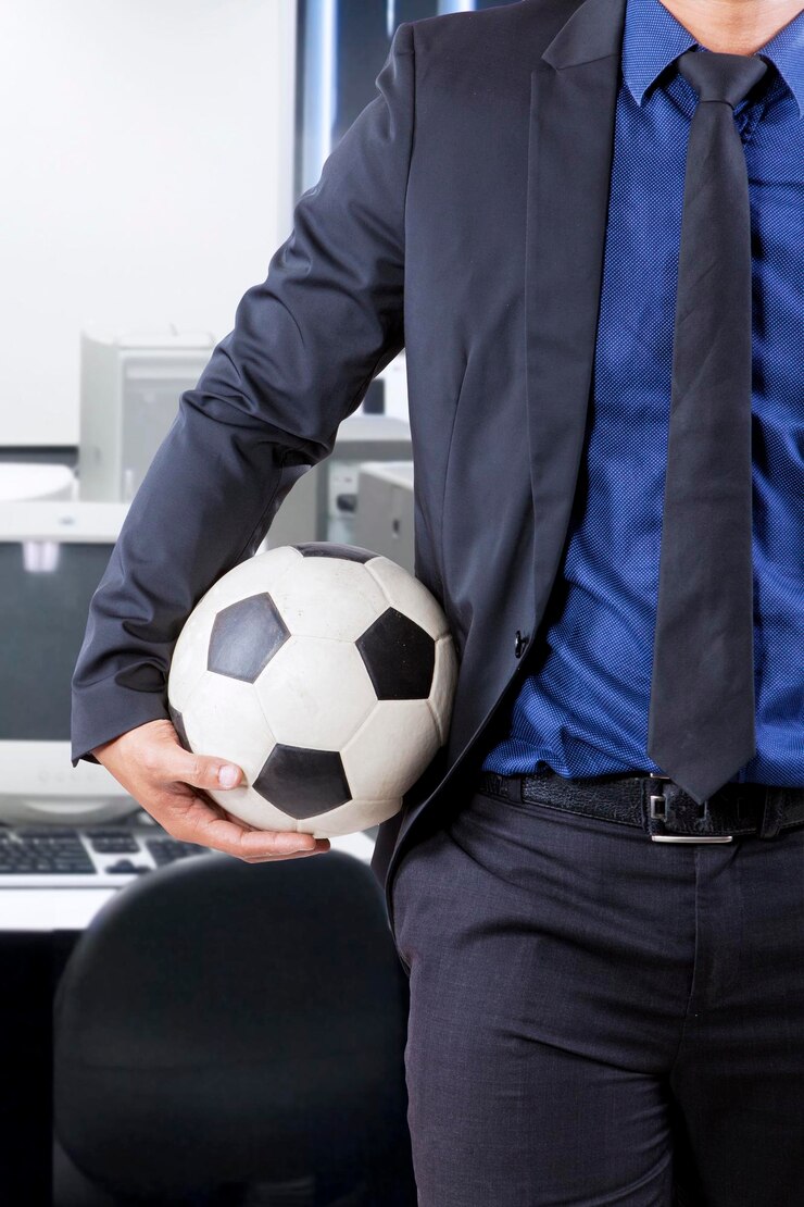 Foto mittelabschnitt eines mannes, der einen fußball auf dem tisch hält