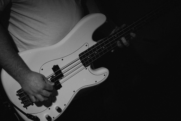 Foto mittelabschnitt eines mannes, der gegen schwarzen hintergrund gitarre spielt