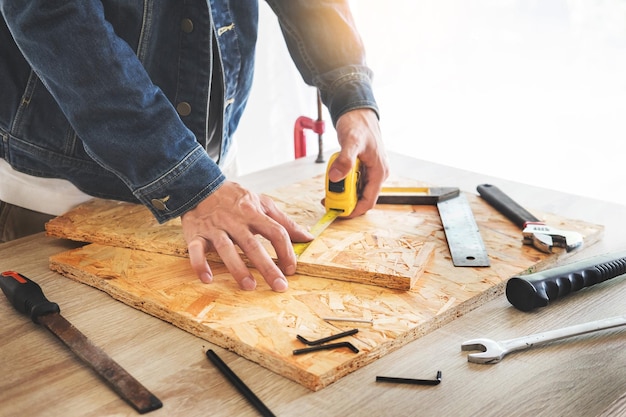 Mittelabschnitt eines Mannes, der Holz mit einem Messband am Werkstuhl misst