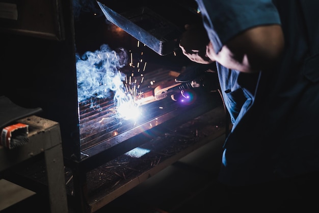 Foto mittelabschnitt eines mannes, der metall in einer fabrik schweißt