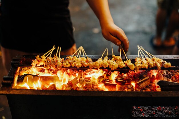 Foto mittelabschnitt eines mannes, der satay auf dem barbecue zubereitet