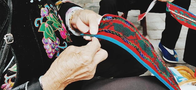 Foto mittelabschnitt eines mannes und haltung des nähens farbenfroher textilwaren