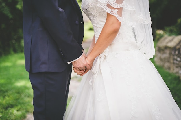 Mittelabschnitt eines Paares, das sich bei einer Hochzeit an den Händen hält