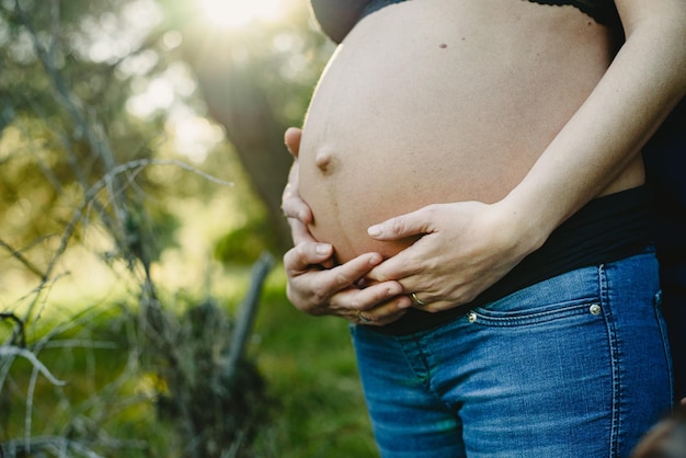 Foto mittelabschnitt eines schwangeren paares, das sich am bauch berührt