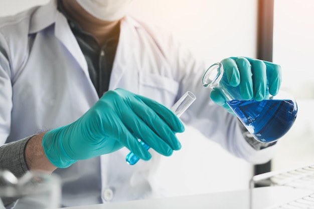 Foto mittelabschnitt eines wissenschaftlers, der eine chemikalie im labor untersucht