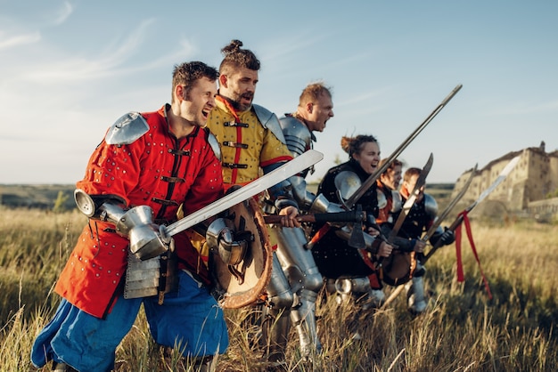 Mittelalterliche Ritter in Rüstung und Helmen, die vor der Schlacht in einer Reihe stehen. Gepanzerter alter Krieger in Rüstung posiert auf dem Feld