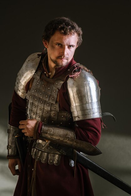 Mittelalterlicher Ritter in Rüstung und Waffe auf dunklem Hintergrund. Porträt des Ritters
