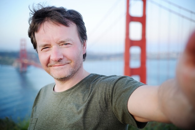 Mittelaltermann, der ein Selbstporträt (selfie) mit berühmter Golden gate bridge in San Francisco, Kalifornien, USA macht