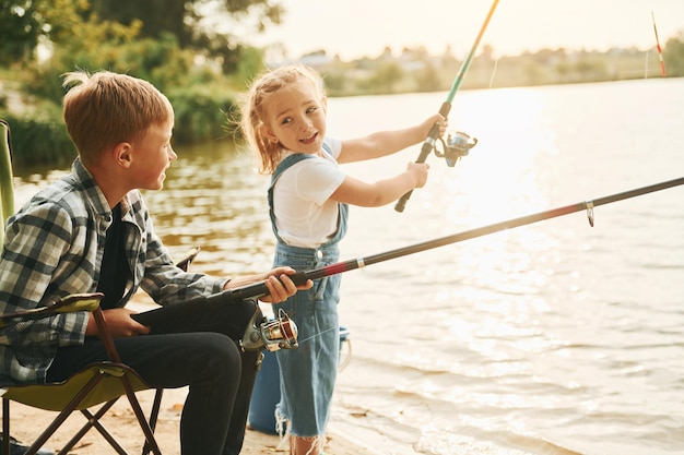 Foto mittelgroßer seejunge mit seiner schwester beim angeln im freien im sommer zusammen