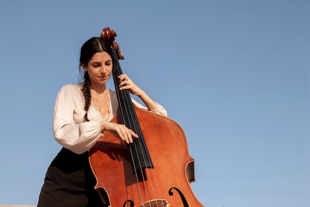 Foto mittelhohe frau, die kontrabass spielt