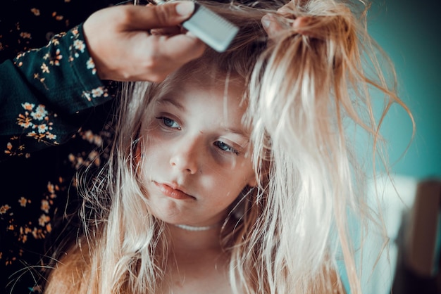 Mittelschnitt einer Mutter, die zu Hause das Haar ihrer Tochter kämmt