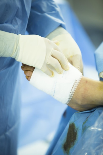 Mittelschnitt eines Arztes, der das Klebeband auf dem Bein eines Patienten im Krankenhaus entfernt