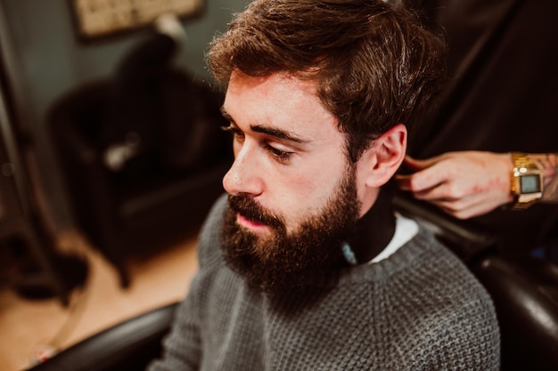 Mittelschnitt eines Friseurs, der einen Kunden im Salon pflegt
