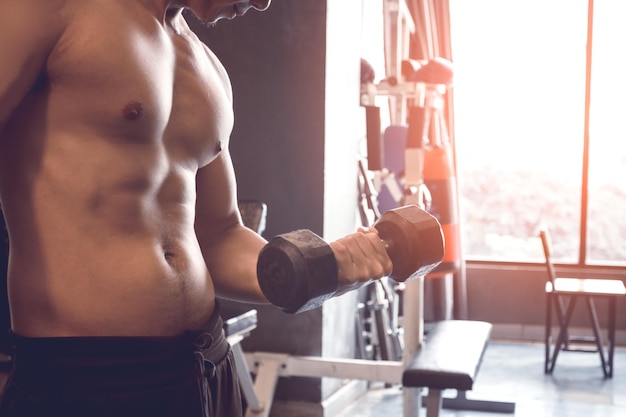 Foto mittelschnitt eines hemdlosen mannes mit hantel im fitnessstudio