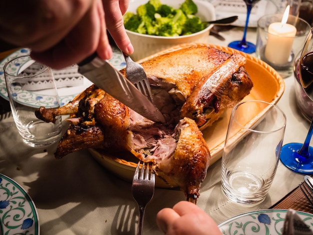 Mittelschnitt eines Mannes, der zum Weihnachten einen Braten Truthahn auf den Tisch schneidet