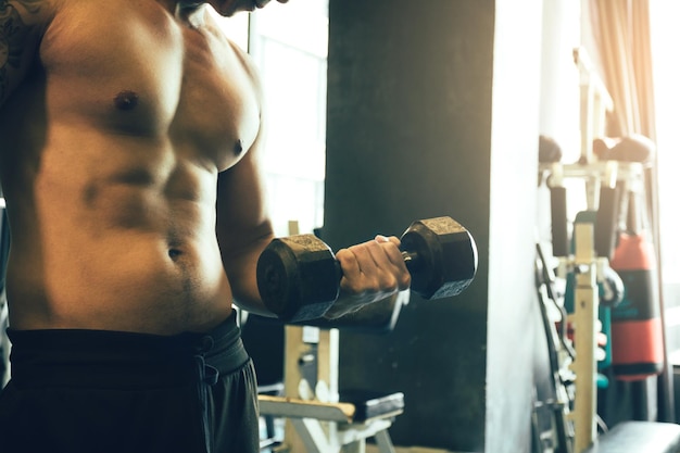 Foto mittelschnitt eines muskulösen männlichen athleten, der sich im fitnessstudio trainiert