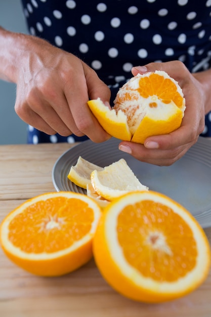 Foto mittelteil der frau, die orange schält