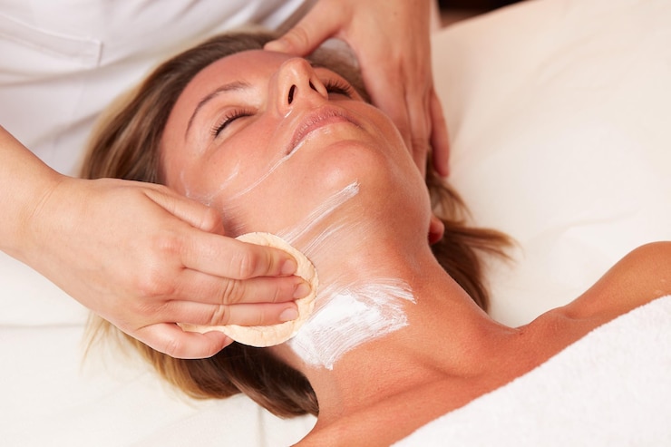 Foto mittelteil der kosmetikerin, die die gesichtsmaske des kunden im spa reinigt