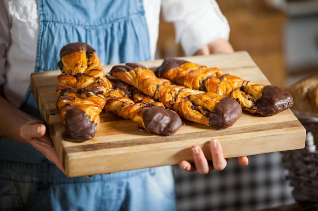 Mittelteil des weiblichen Personals, das süße Lebensmittel in der Bäckerei hält