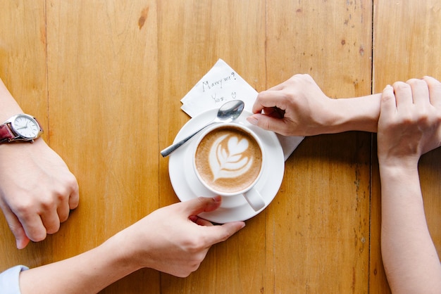 Mittelteil einer Frau, die eine Kaffeetasse auf dem Tisch hält