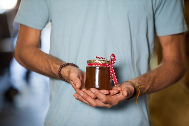 Mittelteil eines Mannes, der ein Glas Marmelade hält