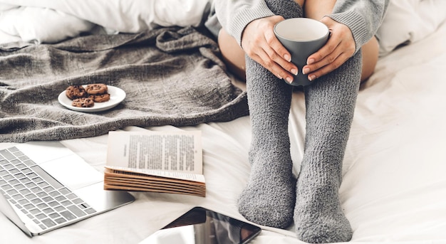 Mittelteil eines Mannes, der eine Kaffeetasse auf dem Bett hält