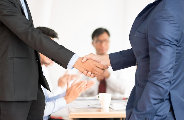 Mittelteil von Geschäftsleuten, die sich während eines Treffens im Büro die Hand schütteln