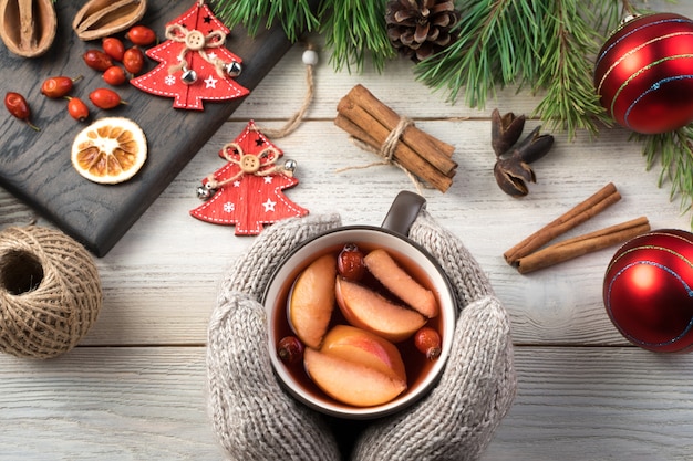 Mittened Hände halten eine Tasse Glühwein.