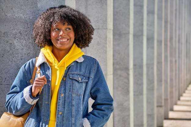 Mittlere Aufnahme eines lächelnden jungen schwarzen Mädchens mit Afro-Haaren, das zur Seite schaut