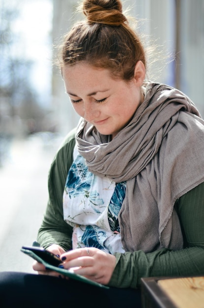 Mittlere erwachsene Frau, die im Winter ihr Mobiltelefon benutzt