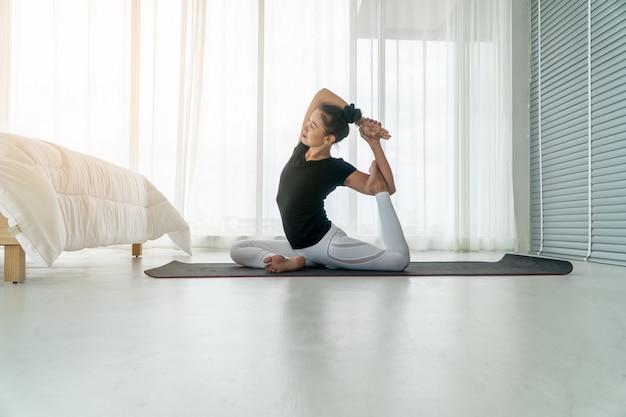 Mittlere Greisinnen, die morgens Yoga im Schlafzimmer, Übung und Entspannung tun.