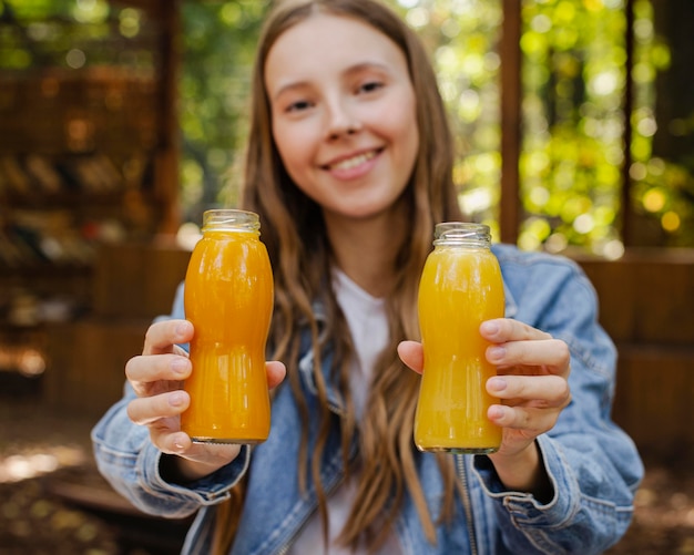 Foto mittlere schuss junge frau, die frische saftflaschen hält