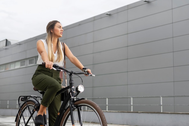 Mittlere Schussfrau, die ihr Fahrrad reitet