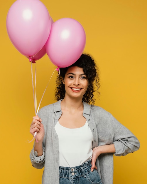 Foto mittlere schussfrau, die mit luftballons aufwirft