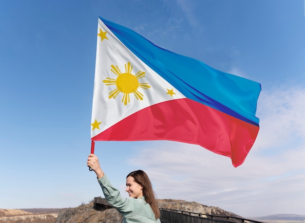 Foto mittlere schussfrau, die philippinische flagge hält