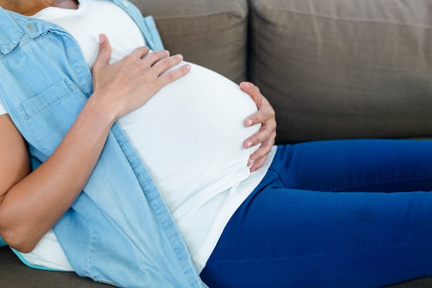 Mittlerer Abschnitt der schwangeren Frau ihren Bauch berührend