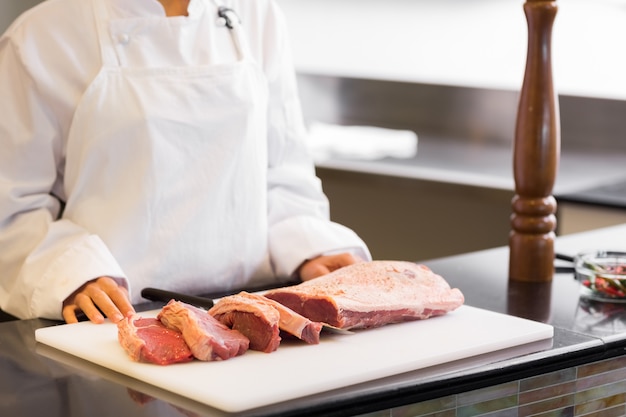 Mittlerer Abschnitt des Chefs mit geschnittenem Fleisch bessert in der Küche aus