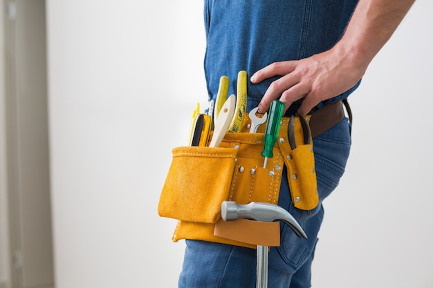 Mittlerer Abschnitt des Heimwerkers mit Toolbelt um seine Taille