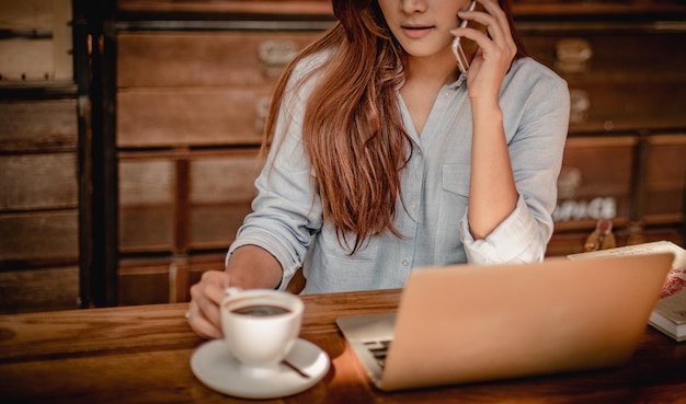 Mittlerer Abschnitt einer Frau, die am Handy am Tisch spricht