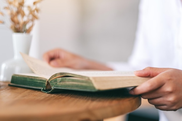 Mittlerer Abschnitt einer Geschäftsfrau, die am Tisch im Café ein Buch liest