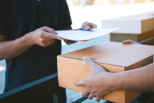 Foto mittlerer abschnitt einer lieferperson, die ein paket an einen männlichen kunden am tor liefert