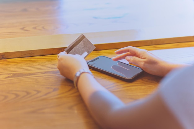 Foto mittlerer abschnitt einer person, die mit mobiltelefonen finanzielle rechnungen auf dem tisch bezahlt