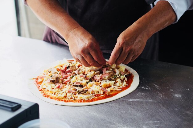 Foto mittlerer abschnitt eines mannes, der hausgemachte pizza für einen restaurant zubereitet