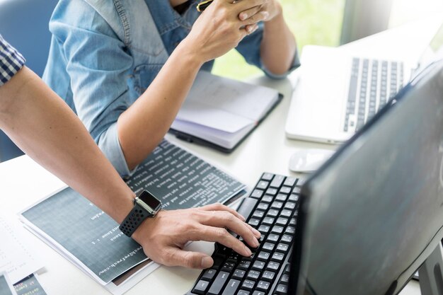 Mittlerer Abschnitt von Computerprogrammierern, die auf einem Tisch sitzend einen Laptop benutzen